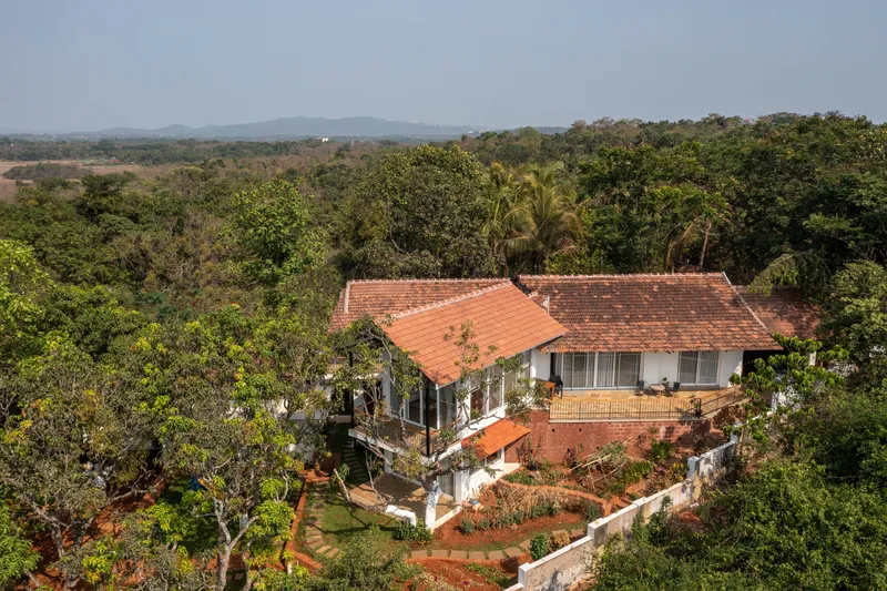 Divar Renovation An aerial view of the extended roofs and surrounding landscape. The living room extension features large windows and cross ventilation nestled among the trees