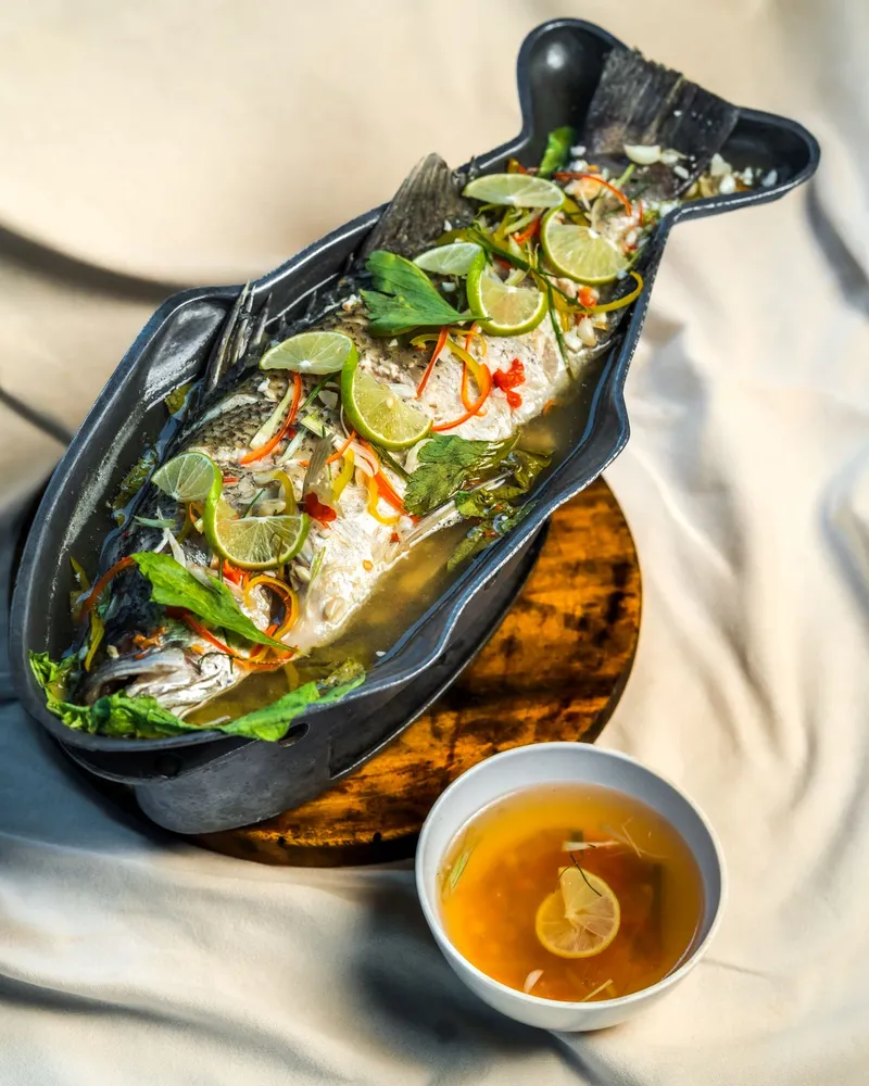 Pla Nuang Manow - Steamed whole fish in spicy lime broth, garnished with fresh herbs and lime slices. (3)