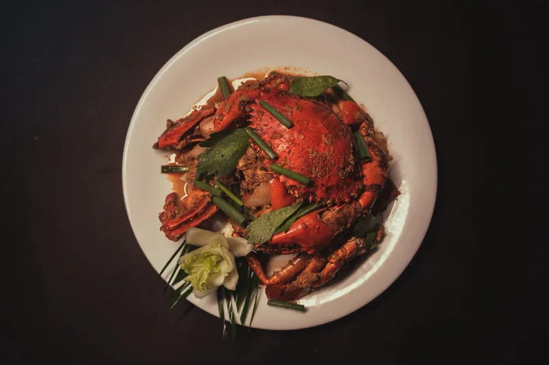 Spicy crab curry stir‑fry, Pad Pong Kari, served with aromatic herbs and a decorative vegetable flower. (2)