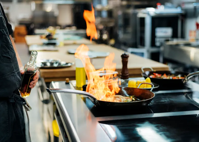 side view chef flambeing dish kitchen