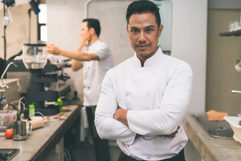 smiling young asian chef kitchen interior