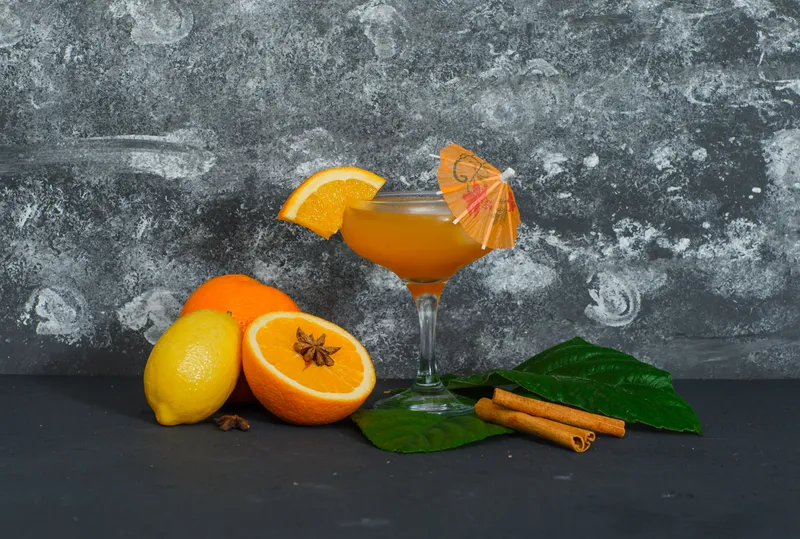 some oranges with juice glass lemon leaves dark textured surface side view