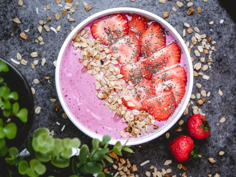 top view healthy breakfast bowl with pink yogurt oats strawberries